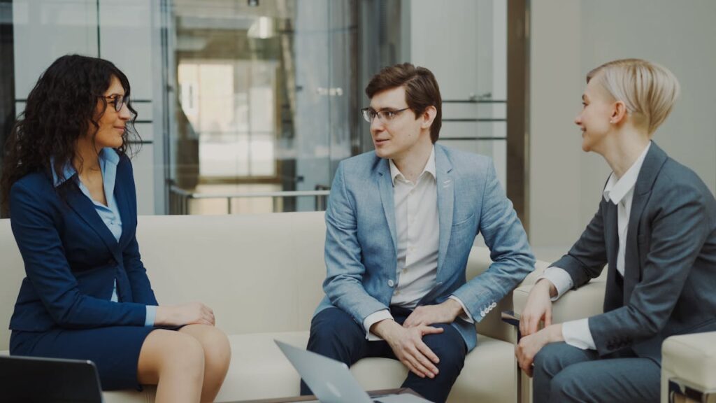Three professionals in a business meeting, discussing ideas in a modern office environment.